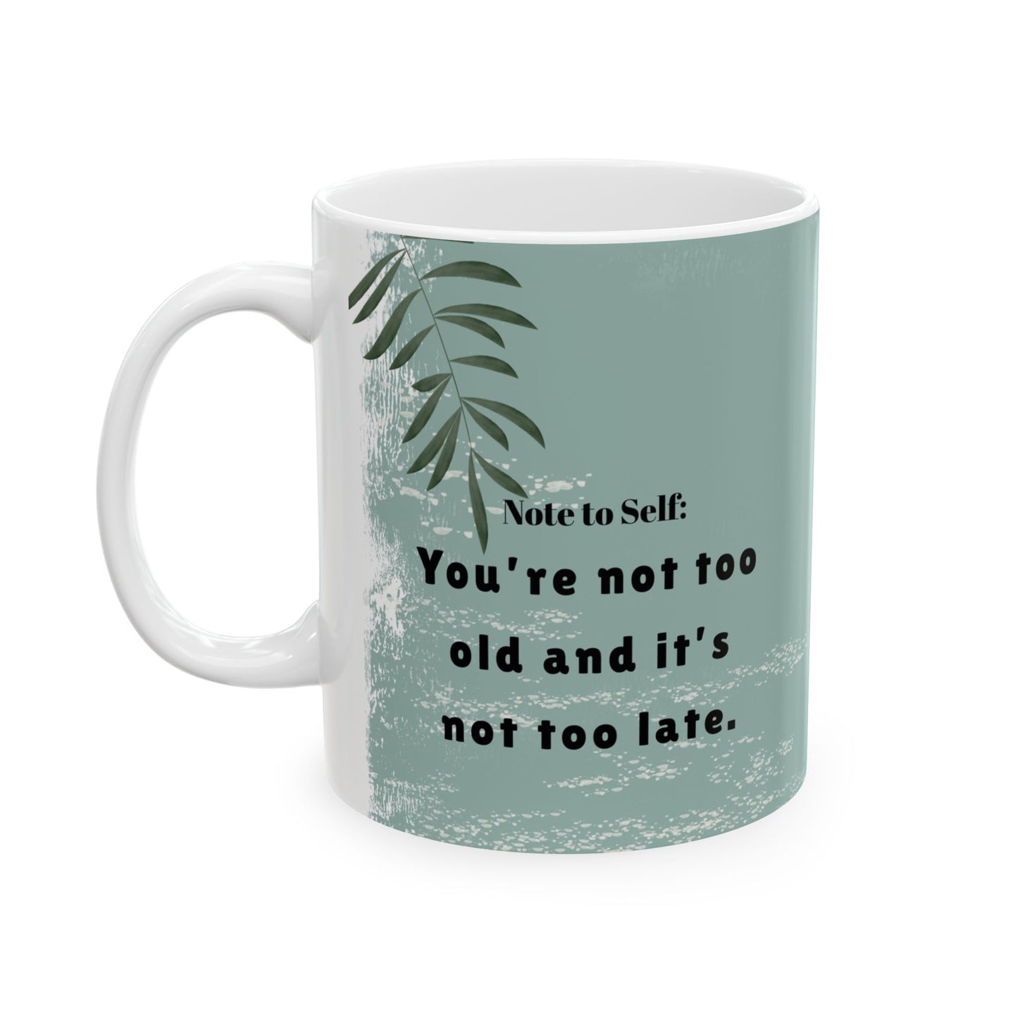 A white ceramic mug with a handle, featuring a sage green background on the right side with a motivational quote, and a white textured background with a green leafy design on the left side. The quote reads "Note to Self: You're not too old and it's not too late." The mug is positioned against a plain white background