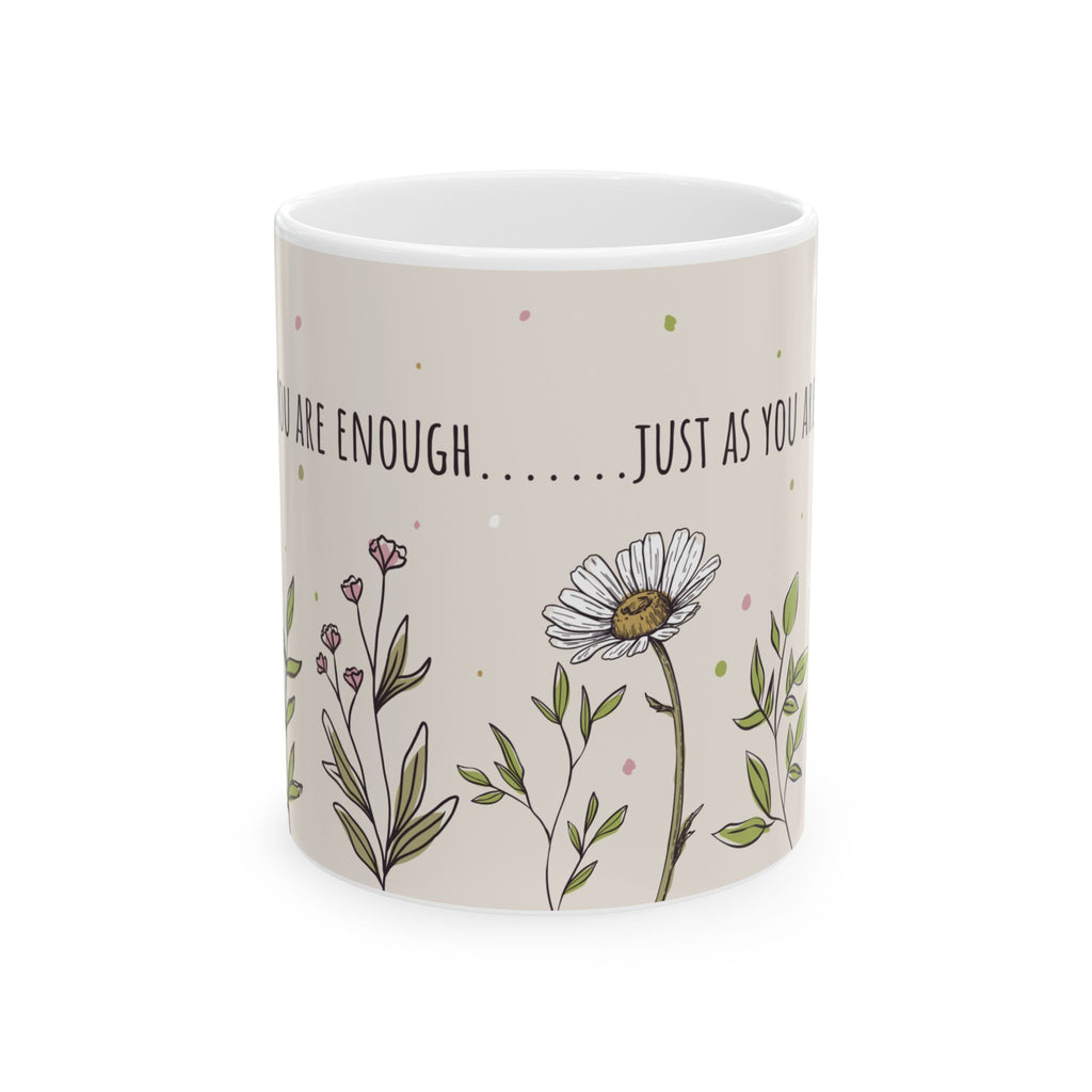 The image shows a white ceramic mug with a beige background, featuring a floral design and an inspirational quote. The quote, partially obscured, reads "ARE ENOUGH.......JUST AS YOU ARE ENOUGH." 
