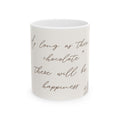  A white ceramic mug with a quote in cursive font that reads "If long as there chocolate there will be happiness" and a small floral design at the bottom right. The mug is photographed against a white background, with soft lighting that highlights the texture of the ceramic.
